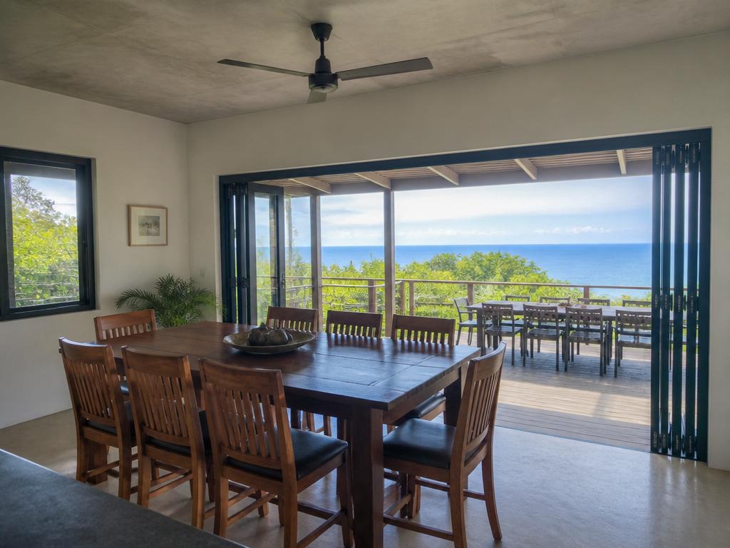 Realistic dining room with authentic wooden table, concrete ceiling, and ocean-view balcony