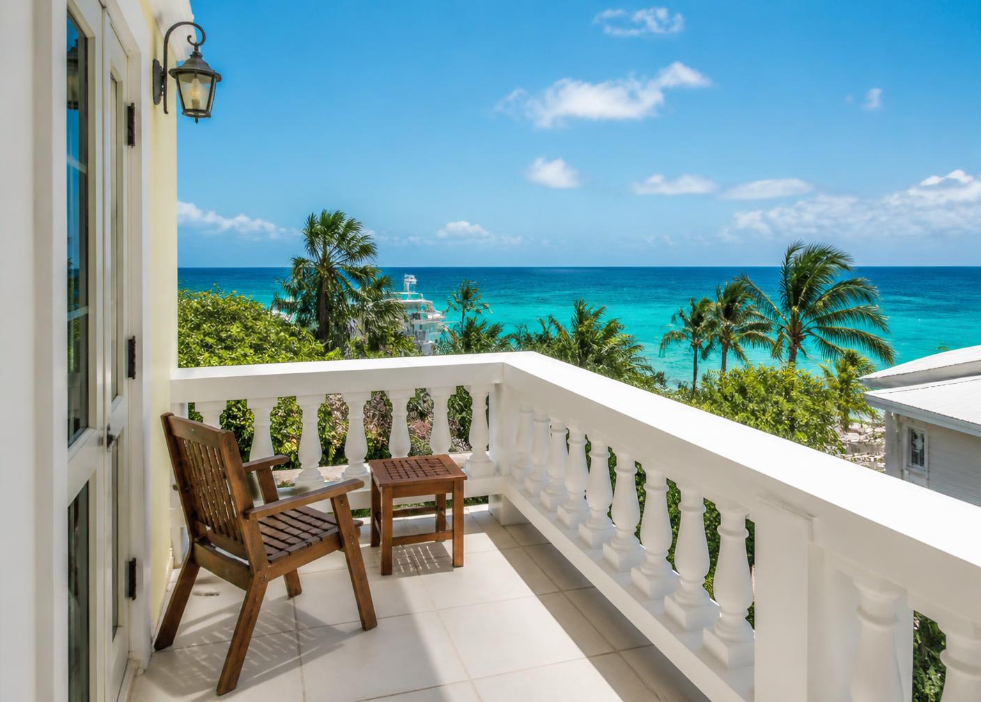 Small second-floor balcony with white railing and ocean view